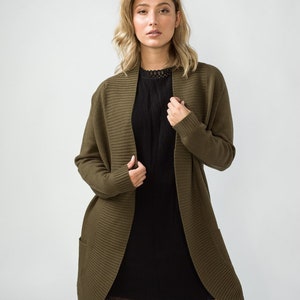 K&ouml;nnte beinhalten: Ein langer, olivgr&uuml;ner Cardigan mit Schalkragen und Taschen. Der Cardigan ist aus weichem, gestricktem Stoff.