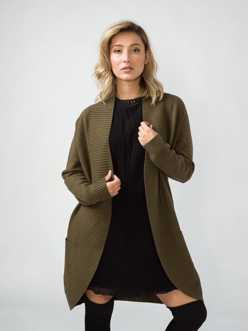 K&ouml;nnte beinhalten: Ein langer, olivgr&uuml;ner Cardigan mit Schalkragen und Taschen. Der Cardigan ist aus weichem, gestricktem Stoff.