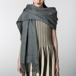 May include: A woman wearing a gray scarf over a black and white striped dress.