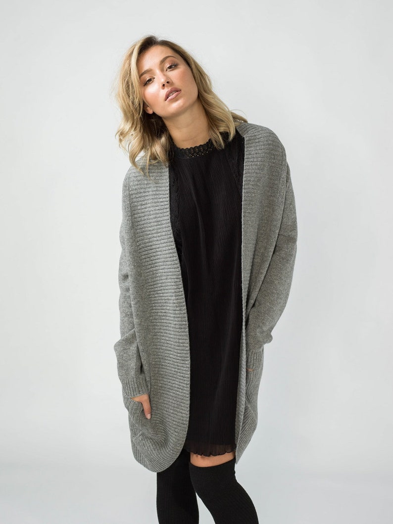 K&ouml;nnte beinhalten: Ein grauer gerippter Cardigan mit langen &Auml;rmeln und Taschen. Der Cardigan ist vorne offen und hat eine lockere Passform.