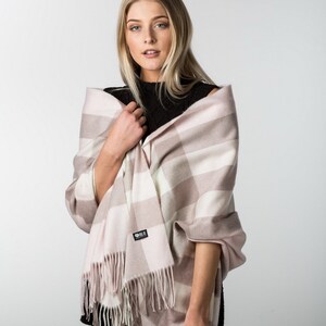 May include: A pink and white plaid scarf with fringe. The scarf is made of soft, warm material and is perfect for keeping you warm in the winter.