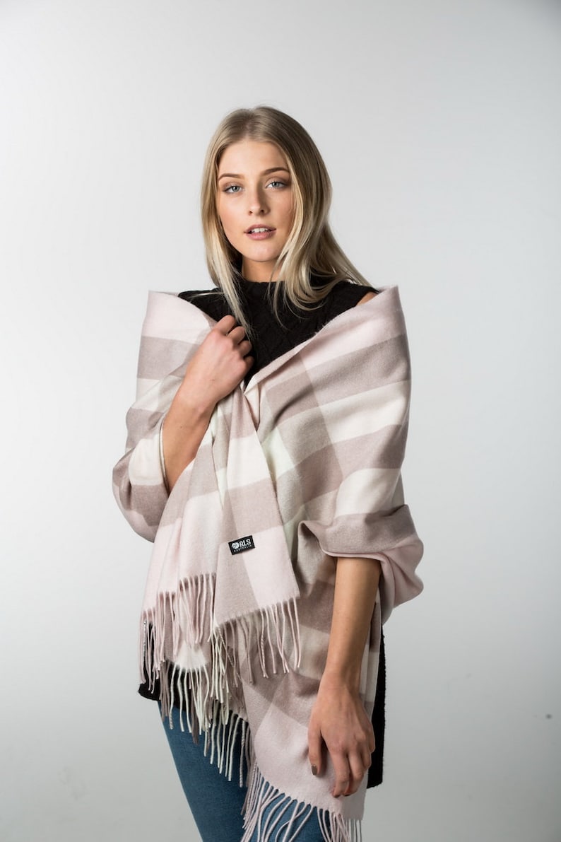 May include: A pink and white plaid scarf with fringe. The scarf is made of soft, warm material and is perfect for keeping you warm in the winter.