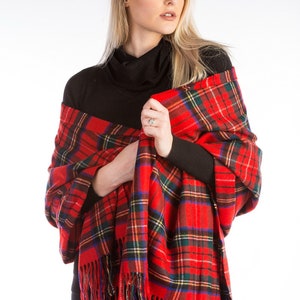 May include: A red and green plaid shawl with fringe. The shawl is draped over a person's shoulders.