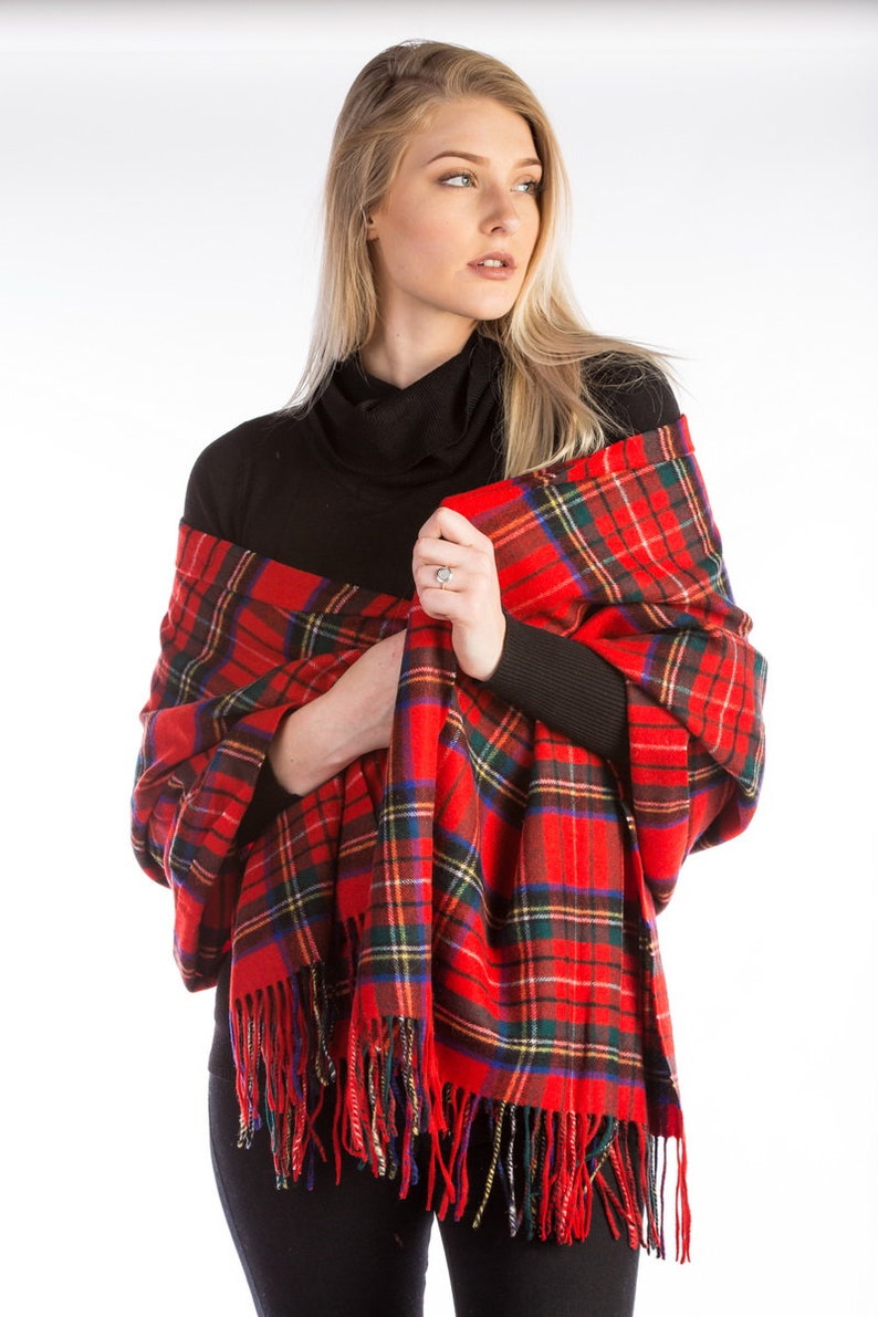 May include: A red and green plaid shawl with fringe. The shawl is draped over a person's shoulders.