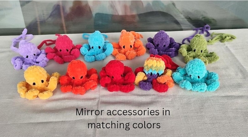May include: A collection of colorful, plush octopus toys in various shades, including purple, pink, blue, orange, yellow, and green. The toys are arranged on a light-colored surface. The text "Mirror accessories in matching colors" is visible at the bottom.