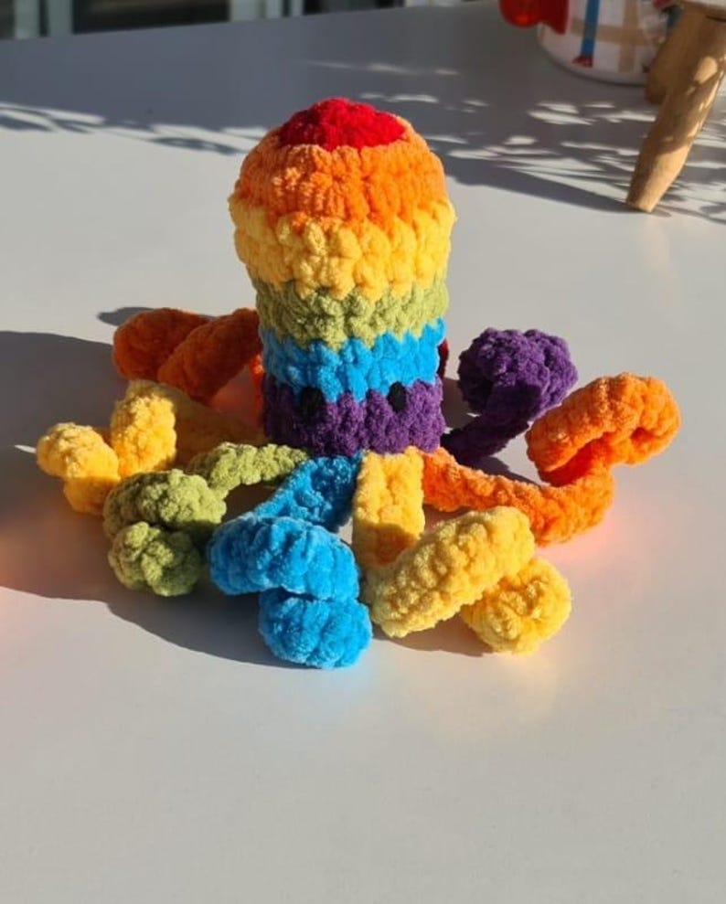 May include: A handmade, colorful crochet octopus toy. The octopus features a rainbow of colors, including red, orange, yellow, green, blue, and purple. The tentacles are also in various colors. This soft toy is suitable for children.