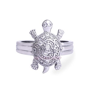 May include: A silver ring with a detailed, sparkling turtle design. The turtle is set on a silver band with a textured finish.