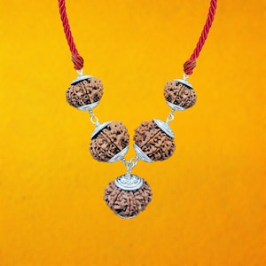 Può includere: Una collana d'argento con cinque perle marroni, ciascuna con intagli intricati. La collana è infilata su un cordoncino rosso.