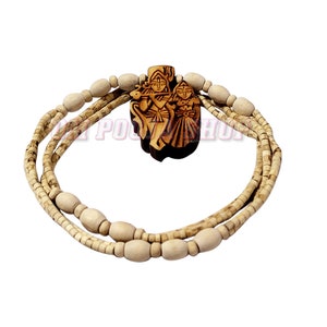 Puede incluir: Un collar de madera con un colgante tallado que representa a una pareja. El colgante es marrón y el collar está hecho de cuentas de color marrón claro.