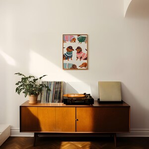 May include: A framed print of a pattern of dachshunds wearing colorful sweaters. The print is hanging on a white wall above a mid-century modern wooden cabinet with a record player on top.