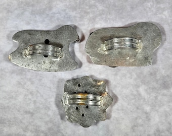 Könnte beinhalten: Drei Vintage-Ausstecher aus Metall in Form eines Schaukelpferds, eines Schafs und eines Sterns. Jeder Ausstecher hat ein Metallband zum Greifen. Die Ausstecher sind silberfarben und weisen Gebrauchsspuren auf.