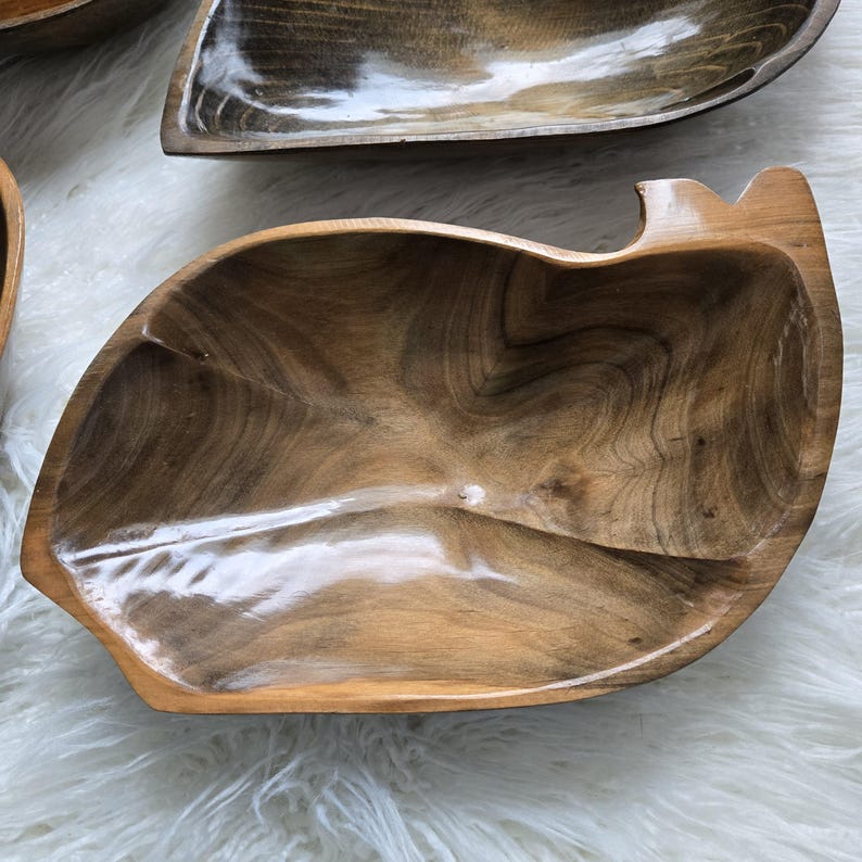 May include: A large, wooden serving bowl with a natural brown finish. The bowl has a unique, organic shape and a smooth, polished surface.