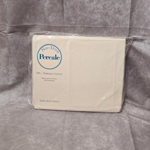 May include: A packaged twin flat sheet in a cream color. The packaging is clear plastic, and the sheet is folded neatly inside. The packaging has a blue and white circular logo that says "No-Iron Percale" and the text "180 - THREAD COUNT".
