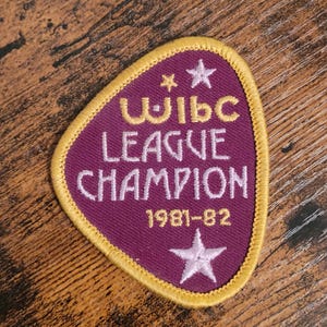 May include: Purple and gold embroidered patch with the text "WIBC League Champion 1981-82" and two stars.