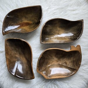 May include: Four wooden bowls in various shapes and sizes. The bowls are all dark brown and have a glossy finish.
