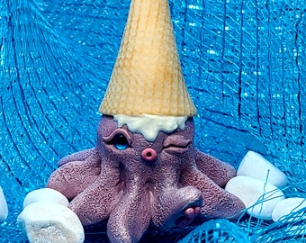 May include: A purple octopus wearing a yellow and white ice cream cone with a white, dripping ice cream topping. The octopus has one eye open and one eye closed, and is winking. The octopus is sitting on a blue and white mesh surface.