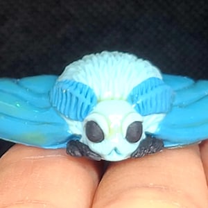 May include: A blue and white hand-painted ceramic moth figurine with detailed wings and antennae.