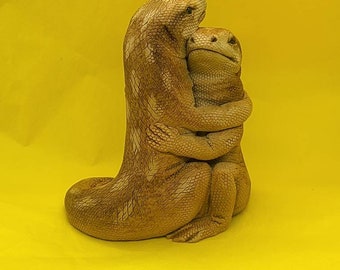 May include: A brown ceramic sculpture of two lizards hugging each other. The lizards are sitting on a yellow surface.