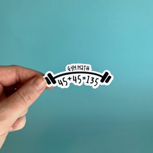 May include: White sticker with black text and a barbell graphic. The text reads "GYM MATH 45+45=135".