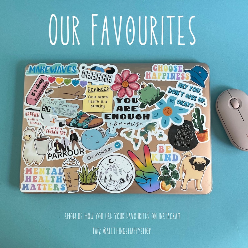 May include: A laptop covered in colorful stickers with various phrases and images, including "Make Waves", "You Are Enough", "Choose Happiness", "Be Kind", and "Mental Health Matters". The laptop is on a blue surface with a white wireless mouse next to it.