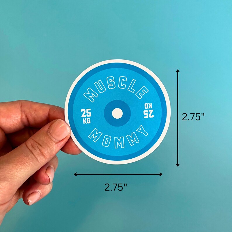 May include: A blue and white round sticker with the text "MUSCLE MOMMY" and "25 KG 52.91" in white. The sticker is 2.75 inches in diameter.