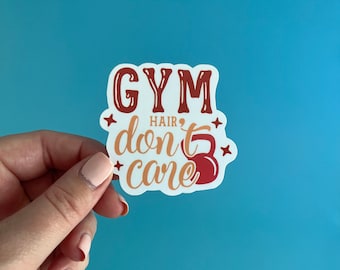 May include: White sticker with the text "GYM HAIR don't care" in red and orange lettering. A red kettlebell is next to the text.