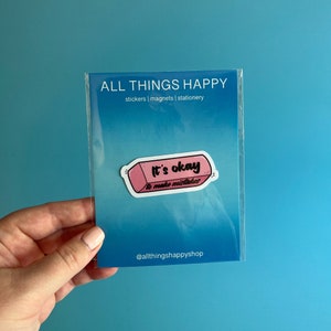 May include: Pink eraser sticker with the text "It's okay to make mistakes" on a white background. The sticker is packaged in a clear plastic sleeve with the text "ALL THINGS HAPPY stickers | magnets | stationery" and "@allthingshappyshop" printed on it.