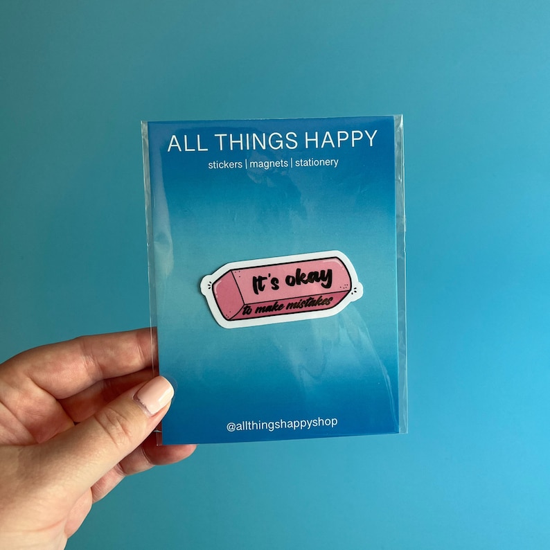 May include: Pink eraser sticker with the text "It's okay to make mistakes" on a white background. The sticker is packaged in a clear plastic sleeve with the text "ALL THINGS HAPPY stickers | magnets | stationery" and "@allthingshappyshop" printed on it.