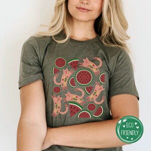 May include: A green t-shirt with a pattern of pink cats and red watermelon slices. The text "Eco Friendly" is on a green circle with white hearts.