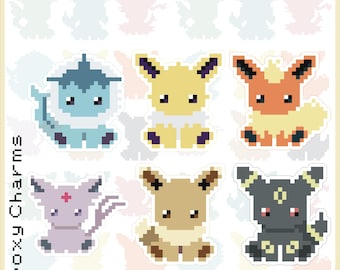 May include: A sheet of 1" glitter epoxy charms featuring pixelated designs of various creatures. The text "Mystery Eeveelution Keychains!" is at the top. The charms are in various colors, including blue, yellow, orange, and purple.