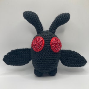 May include: Black crocheted moth plush toy with red beaded eyes.