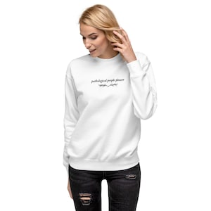 May include: White sweatshirt with the text "pathological people pleaser" in black lettering with a small floral design above and below the text.