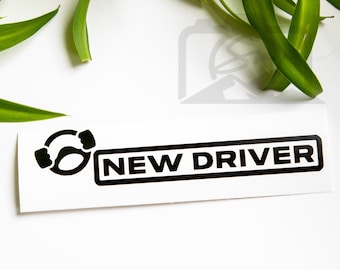 May include: Black and white sticker with a steering wheel icon and the text "NEW DRIVER".