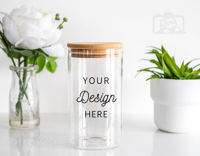 May include: A clear glass jar with a bamboo lid. The jar has the text "YOUR Design HERE" printed on the side. The jar is sitting on a white surface.