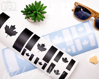 May include: Two sheets of white sticker paper with black and white Canadian flag designs. The black sheet has multiple black maple leaves and rectangles. The white sheet has multiple white maple leaves and rectangles.