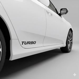 May include: White car with a black "TURBO" decal on the side. The vehicle features black alloy wheels and a side mirror. The image is taken from a low angle, showcasing the car's design.
