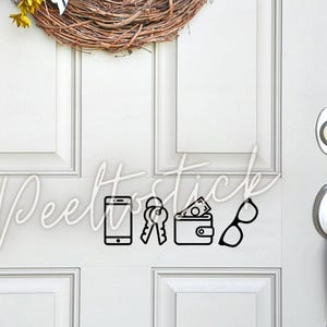 May include: A white door with a black vinyl decal of a phone, keys, wallet, and glasses. The decal says "Peelstick".
