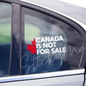 Może przedstawiać: Biała naklejka winylowa z czerwonym liściem klonu i tekstem "CANADA IS NOT FOR SALE" na szybie samochodu.