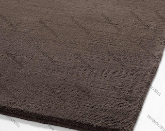 May include: A close-up of a brown rug with a textured surface. The rug has a solid colour and a soft appearance. The rug is made of a thick material and is suitable for home decor.