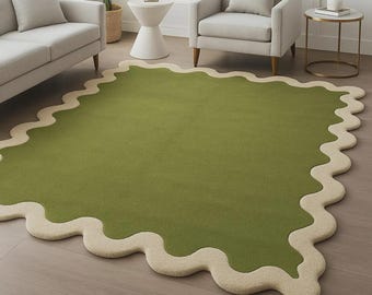 May include: A large, green area rug with a unique, wavy, cream-colored border. The rug is placed on a hardwood floor and is surrounded by furniture, including a sofa and armchair. The rug's design adds a modern touch to the room.