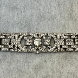 Può includere: Un braccialetto d'argento con un design geometrico e strass trasparenti. Il braccialetto ha una chiusura sul lato destro.