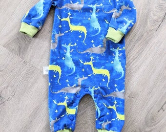 May include: A blue baby onesie with a green trim and a pattern of yellow and grey dragons on a blue background.