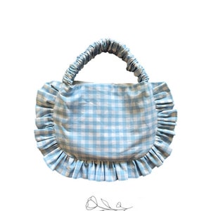 May include: A light blue gingham tote bag with a ruffled edge and a gathered fabric handle.