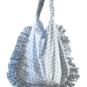 May include: A light blue gingham tote bag with a ruffled trim and a gathered handle.