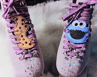 Peut inclure: Une paire de patins à roulettes violets avec des paillettes scintillantes sur les côtés. Un patin a un patch de Cookie Monster et l'autre a un patch de cookie.