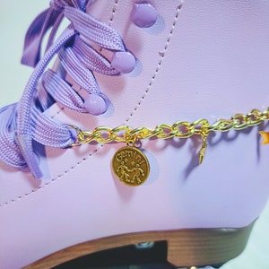 May include: Purple roller skates with a gold chain and a gold charm that says "Gemini" with a symbol of two people holding hands.