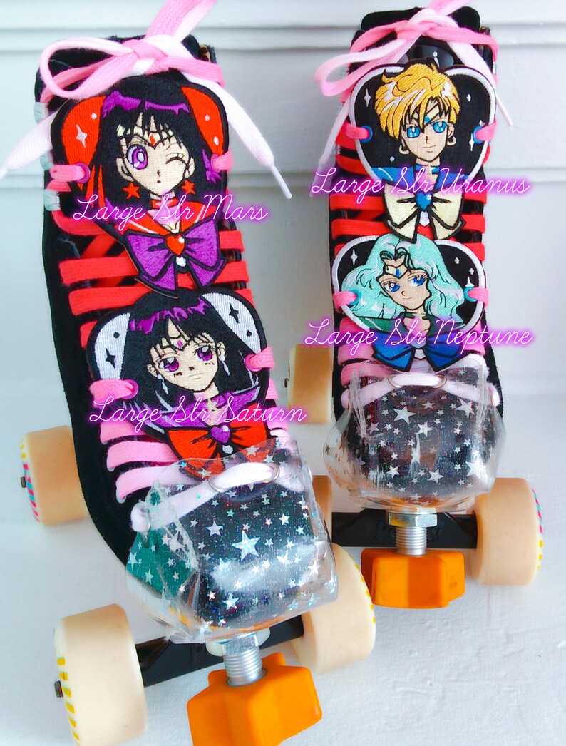 May include: Pair of black roller skates with pink laces and orange wheels. The skates feature anime character designs with the text "Large Slr Mars", "Large Slr Uranus", "Large Slr Neptune", and "Large Slr Saturn". The toe stops are clear with a star pattern.