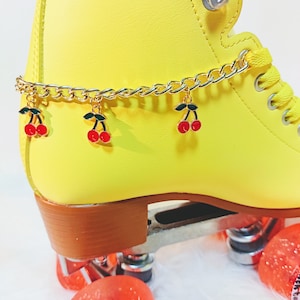 May include: Yellow roller skate with a gold chain and red cherry charms. The skate has red wheels with the text "Roller Skates 78A" printed on one wheel.