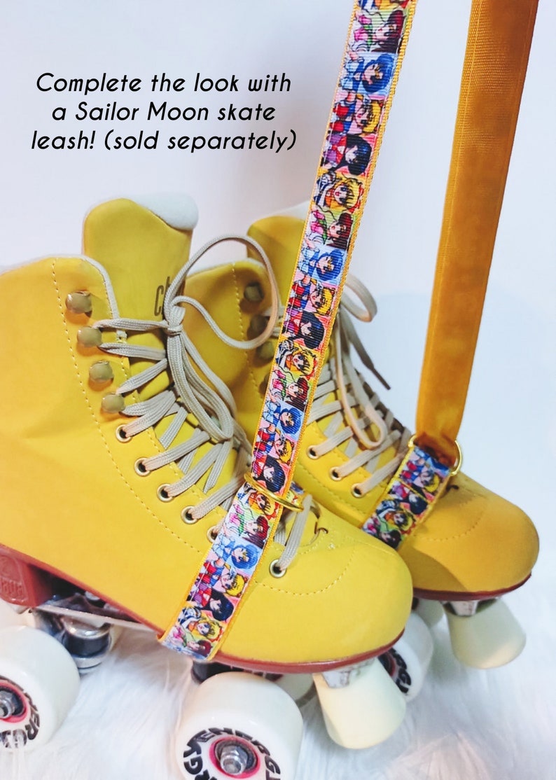 May include: Yellow roller skates with a Sailor Moon skate leash. The leash features a colorful pattern of Sailor Moon characters. The skates have white wheels and beige laces. The text on the image says "Complete the look with a Sailor Moon skate leash!"