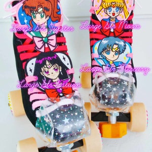 May include: Pair of custom roller skates featuring black uppers with pink laces and accents. Each skate has a clear toe stop filled with glitter and star details. Patches of Sailor Moon characters are sewn onto the tongues, with the text "Large Str Jupiter", "Large Str Moon", "Large Str Mercury", and "Large Str Saturn".